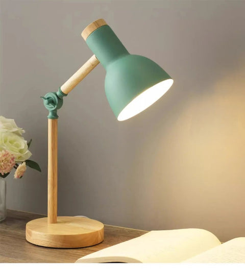 Green Nordic wooden desk lamp beside a vase of flowers