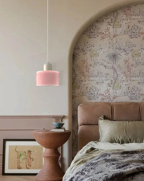 Pink glass pendant light hanging beside a bed