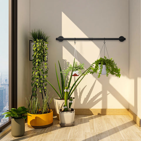 Black pipe clothes rail on a dark wall beside plants
