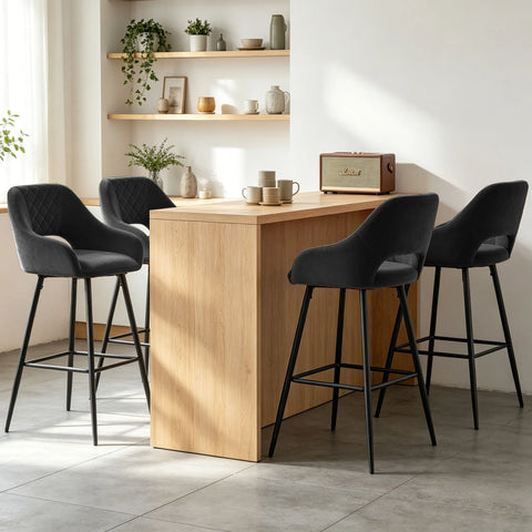 Four black velvet quilted bar stools with arms at a wooden counter