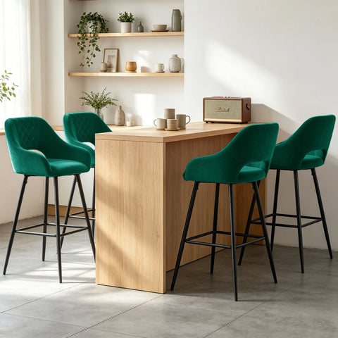 Four green velvet quilted bar stools with arms at a wooden counter