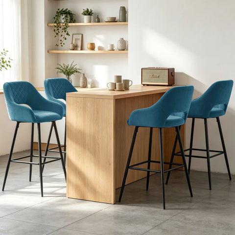 Four teal velvet quilted bar stools with arms at a wooden counter
