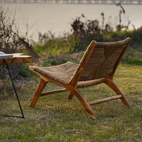 Woven rattan lounge chair outdoors on grass