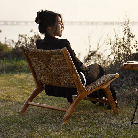 Someone seated in the woven rattan lounge chair outdoors