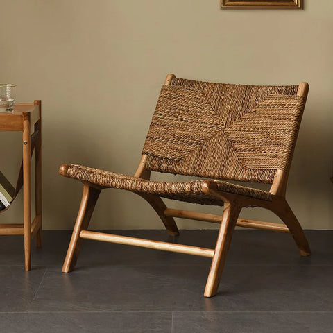 Woven rattan lounge chair with a teak frame on a wooden floor