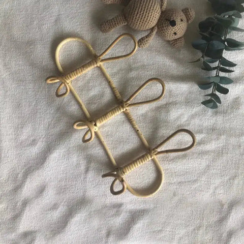 Rattan wall hook rack with three looped hooks, styled with dried stems