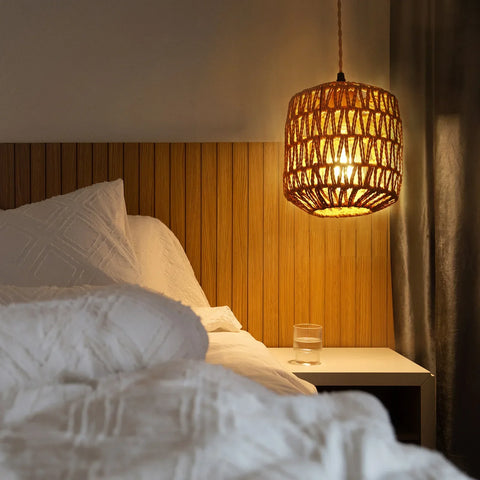 Rattan wall lamp lit above a bed