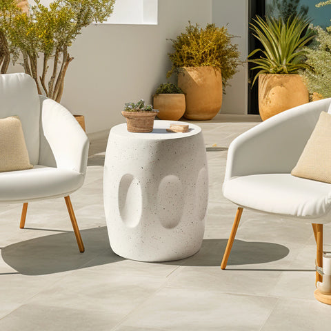 Round concrete side table beside a cream armchair