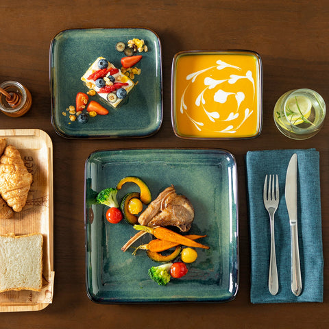 Table laid with square green glaze plates and a meal