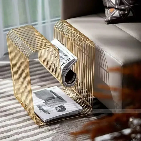 Gold wire side table beside a bed holding magazines
