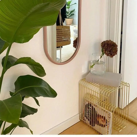 Gold wire side table in a hallway beneath a round mirror