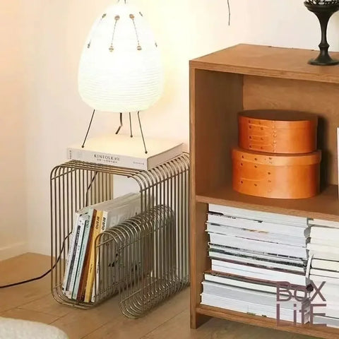 Gold wire side table holding magazines beside a shelving unit