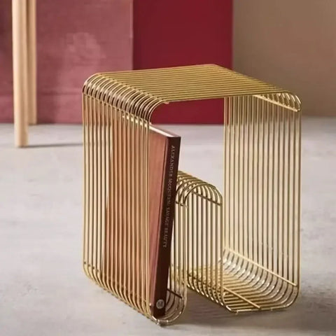 Gold wire side table against a red wall