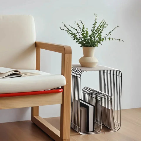 Silver wire side table with a plant and books beside an armchair