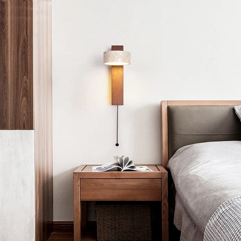 Stone-shade wall lamp above a bedside table