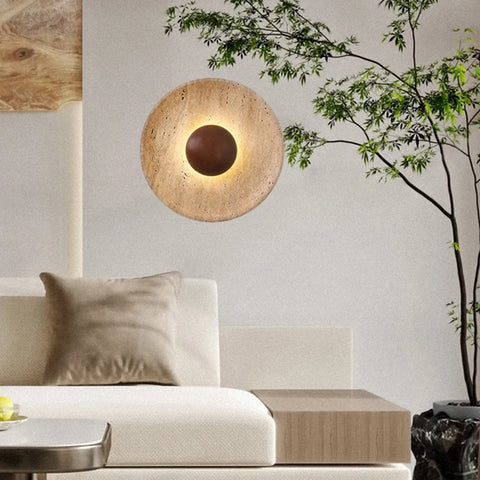 Stone and wood wall light above a bed with a plant