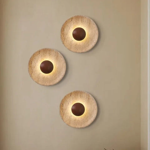 Three stone and wood wall lights grouped on a neutral wall