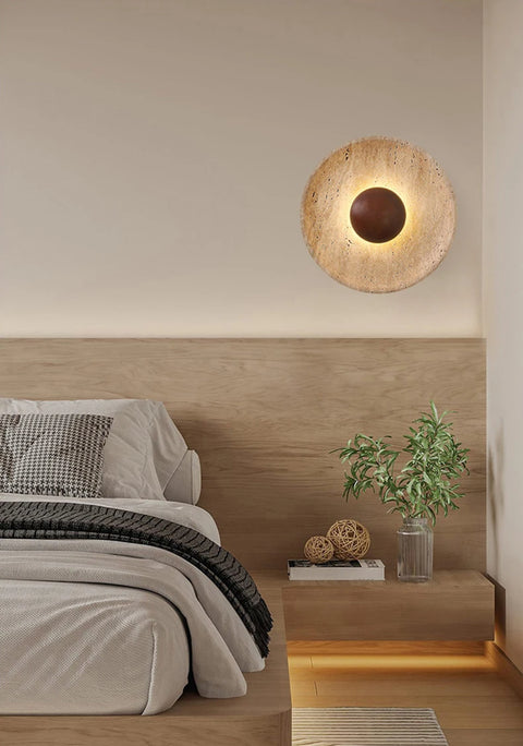 Stone and wood wall light lit above a bed