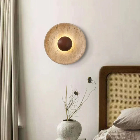 Stone and wood wall light above a bed with a vase