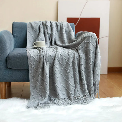 Light grey tasselled knitted throw over a blue armchair
