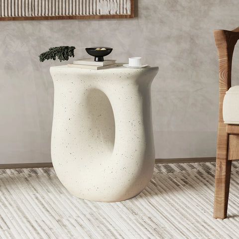 U-shaped off-white concrete side table beside a bed