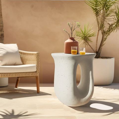 U-shaped concrete side table beside a rattan chair