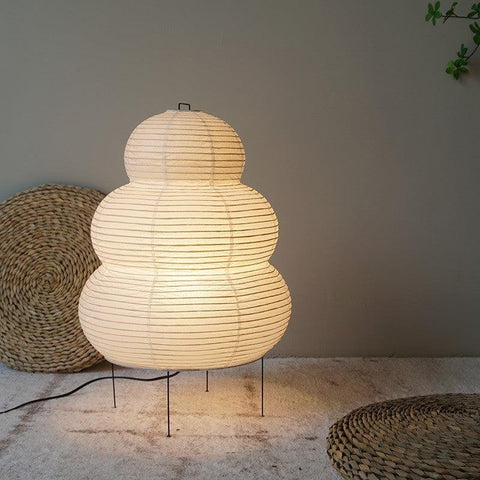 Tiered paper lantern lamp lit on a woven mat