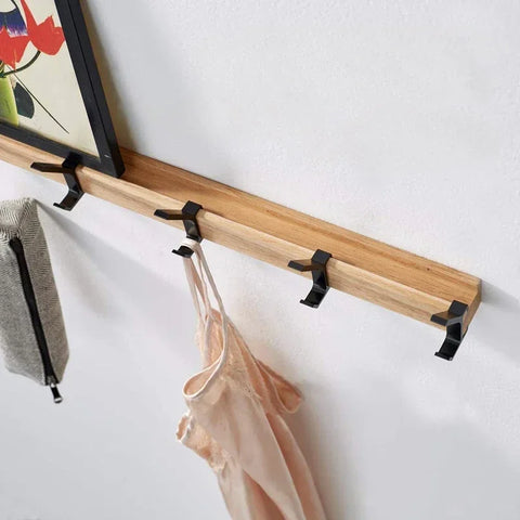 Folding coat hooks holding a jacket and bag against a white wall