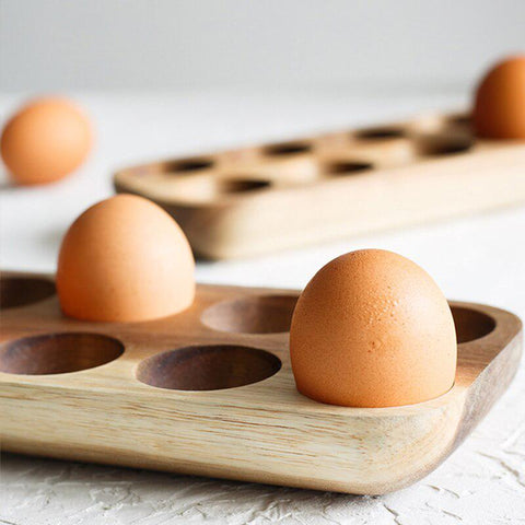 Wooden egg tray holding eggs on a wooden board