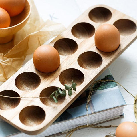 Twelve-hole wooden egg tray with eggs on a linen cloth