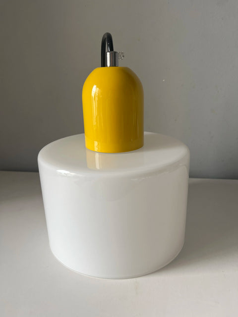 White glass pendant light with a mustard cap, close-up