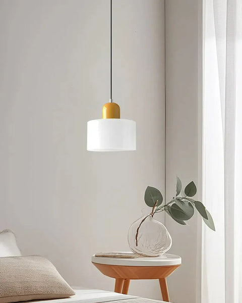 White glass pendant light with a mustard cap above a side table