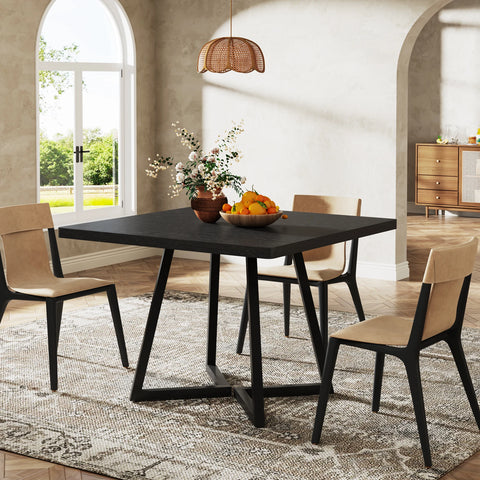 Black dining table with a bowl of fruit and four chairs