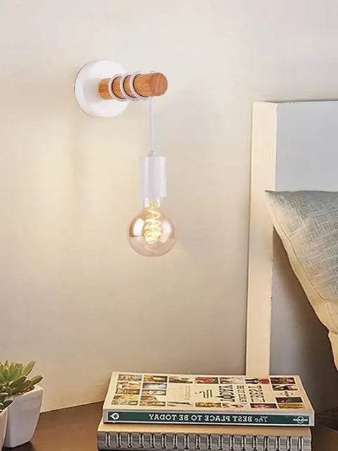 Wooden bead wall sconce in pale wood beside a bed