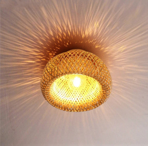 Woven bamboo ceiling lamp lit, casting a patterned shadow on the ceiling