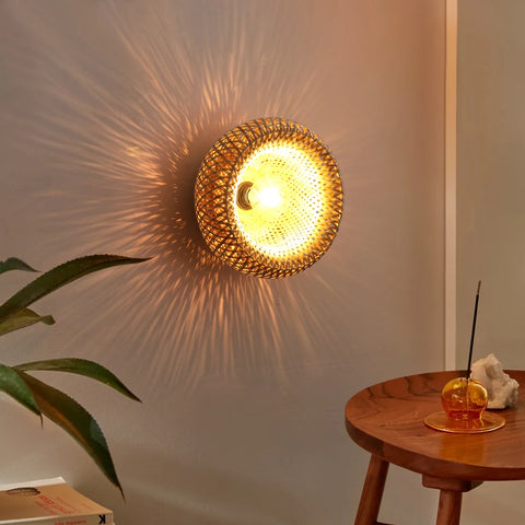 Woven bamboo ceiling lamp lit above a side table and plant