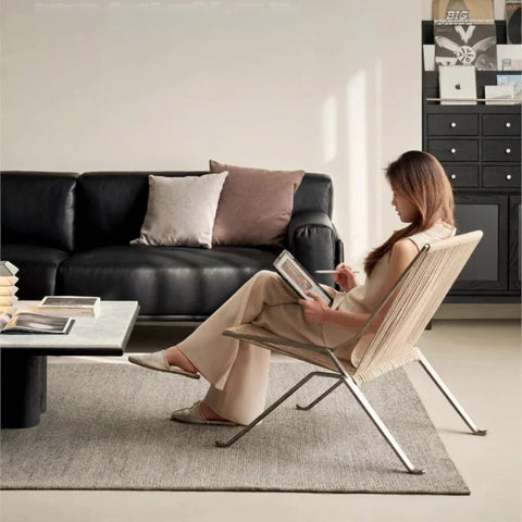 Someone seated in the woven cord lounge chair beside a sofa