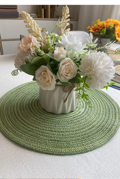 Green woven round placemat under a vase of flowers