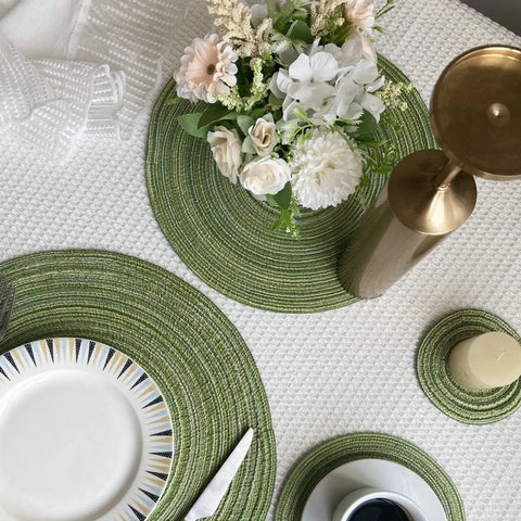 Green and cream woven placemats with plates and flowers