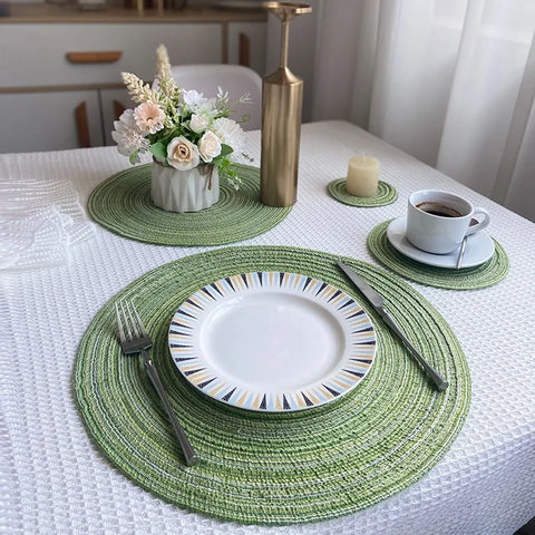 Green yarn woven placemats on a white tablecloth with plates