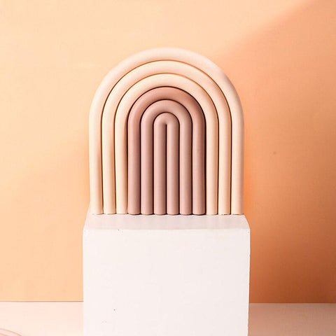 Pink arch-shaped coaster standing against a warm background
