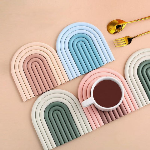 Arch-shaped coasters in blue, green and pink with a mug and cutlery