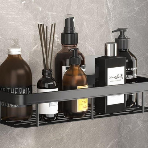 Black bathroom shelf holding a reed diffuser and bottles