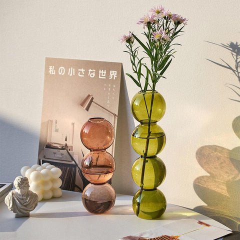 Bubble glass vases holding cut flowers on a shelf