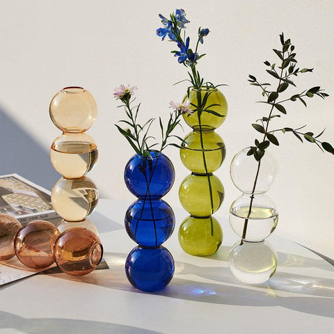 Bubble glass vases in blue, olive, clear and amber holding fresh flowers