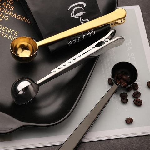 Black coffee scoop clip on a dark tray with coffee beans