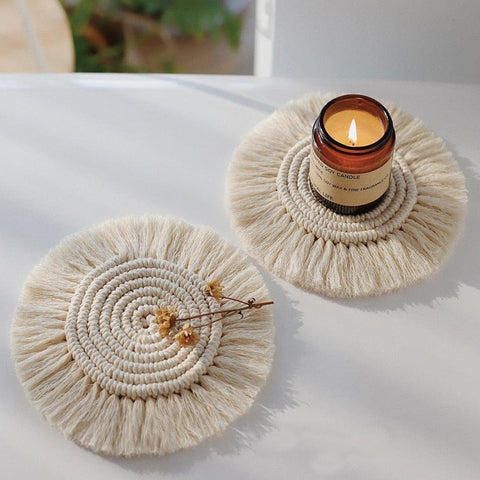 Braided cotton coaster with fringe, holding a lit candle