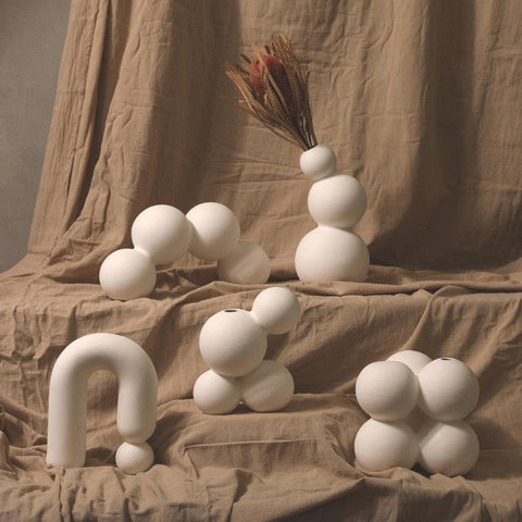 Droplet ceramic vases grouped against a beige drape