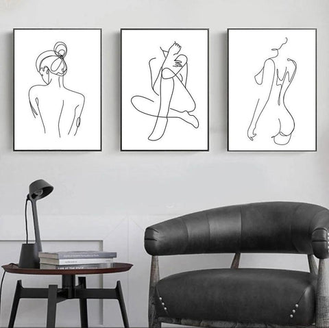 Three female line-drawing prints in black frames above a leather chair