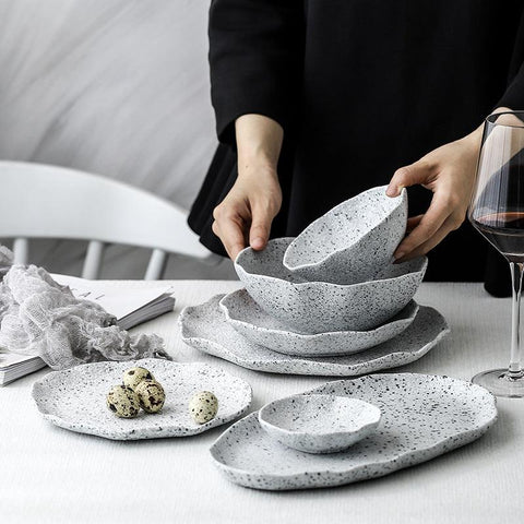Speckled granite stoneware plates and bowls being served at a dark table